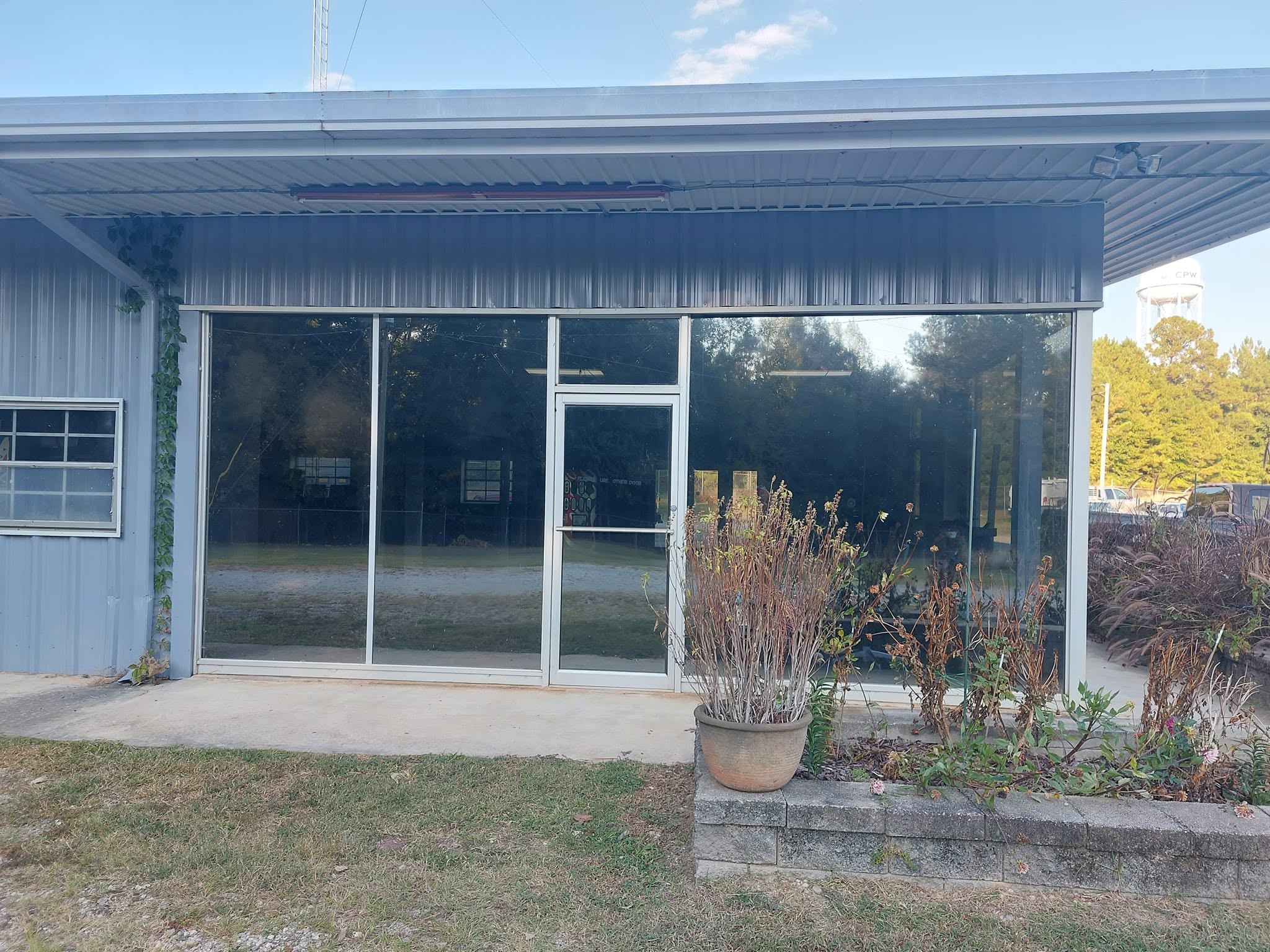 Modern metal building with large glass storefront doors and windows overlooking landscaped grounds