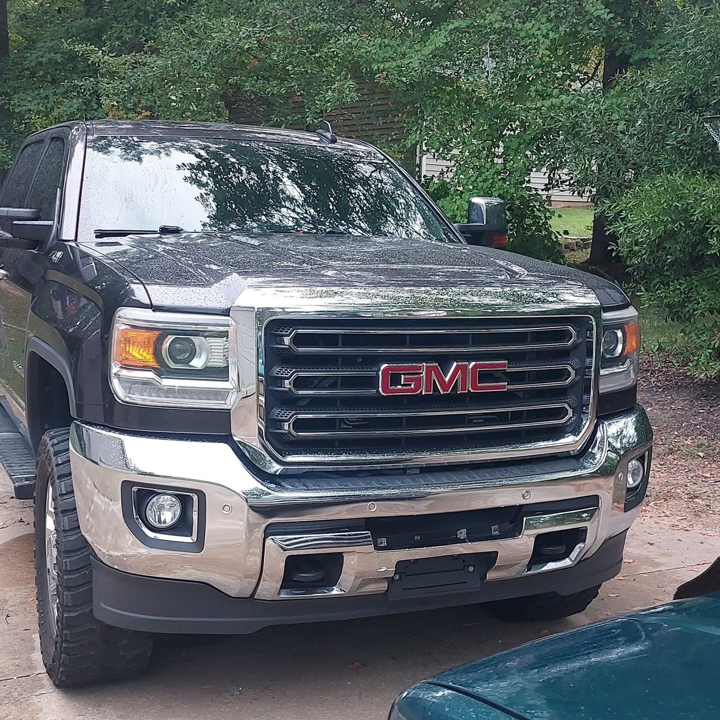Two-tone GMC pickup truck parked in driveway with green foliage background