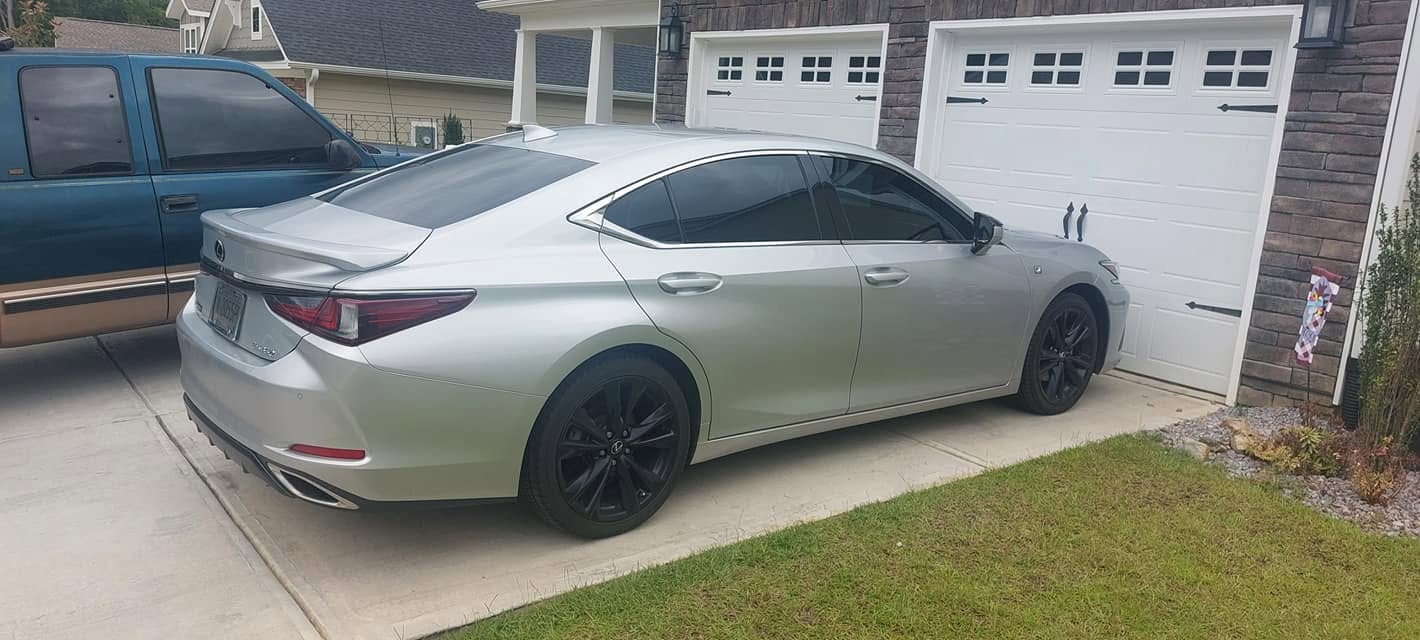 Silver Lexus sedan parked in residential driveway with garage doors in background