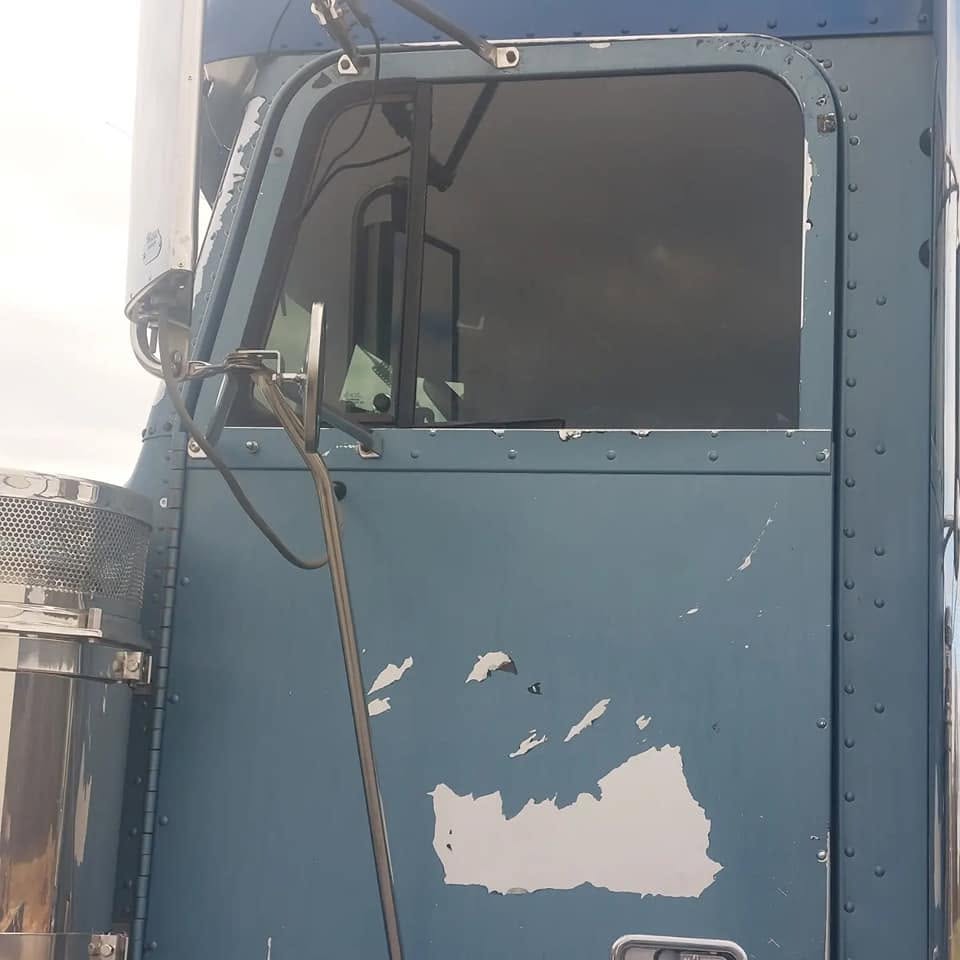 Blue truck door with peeling white paint and rust damage