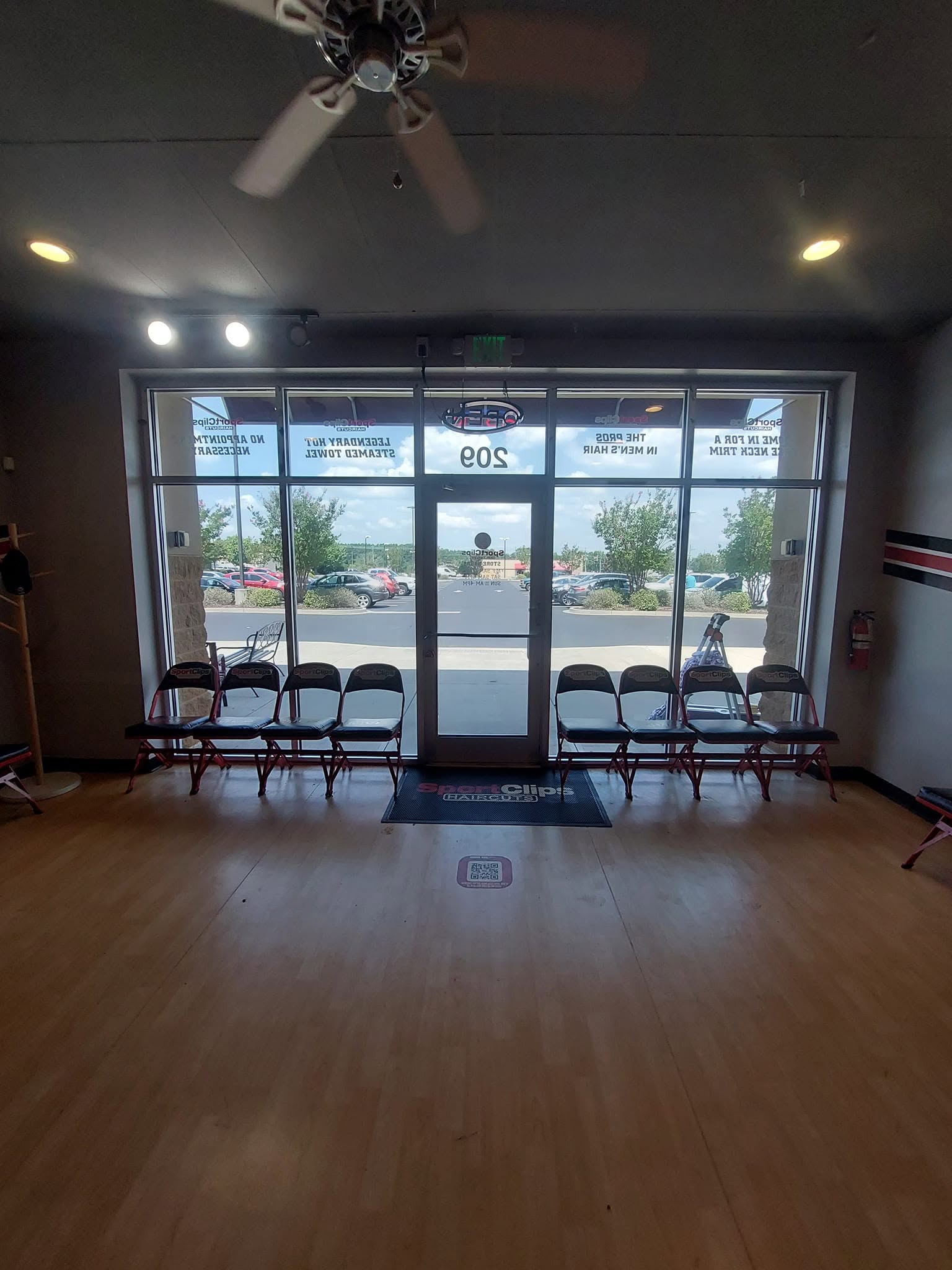 Interior view of a business entrance with glass doors, waiting chairs, and parking lot visible through windows