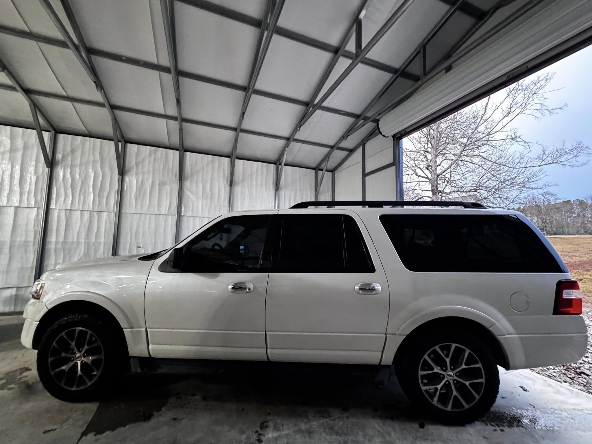 White SUV parked inside metal carport with polycarbonate roof panels