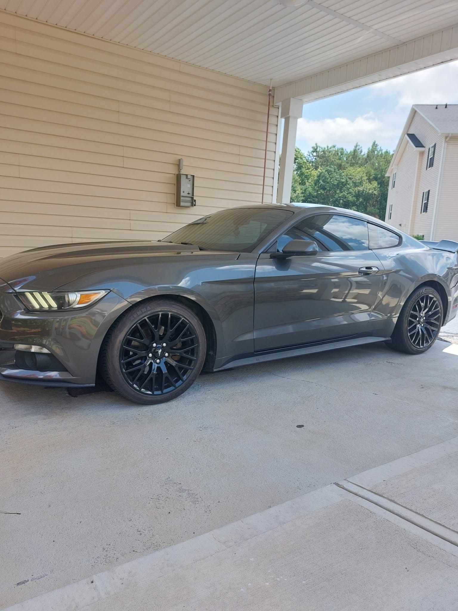 Gray Ford Mustang coupe parked in driveway with open door